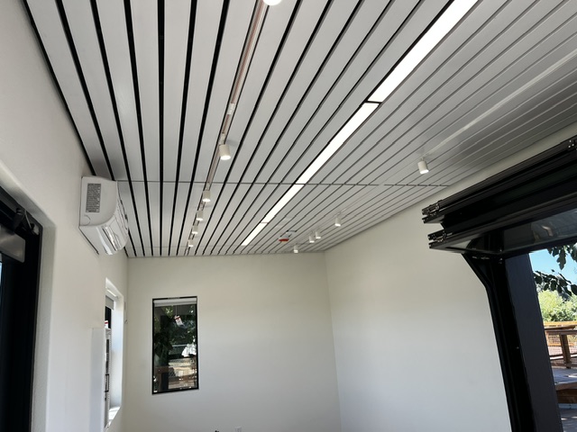 Ceiling detail inside a custom modular building at Dos Rios State Park with linear lighting and a wall-mounted heating and cooling unit