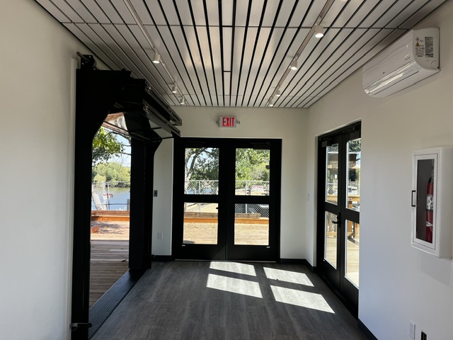 Interior of a custom building at Dos Rios State Park with a slatted ceiling, track lighting, and glass double doors