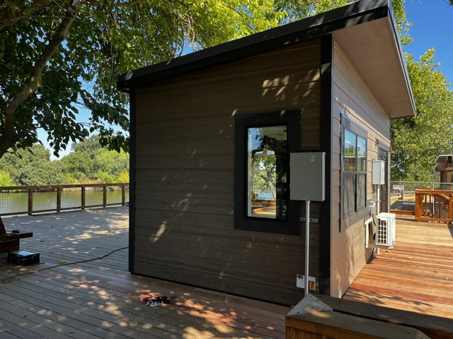 Side view of a custom modular building at Dos Rios State Park with a black-framed window and outdoor heating and cooling unit